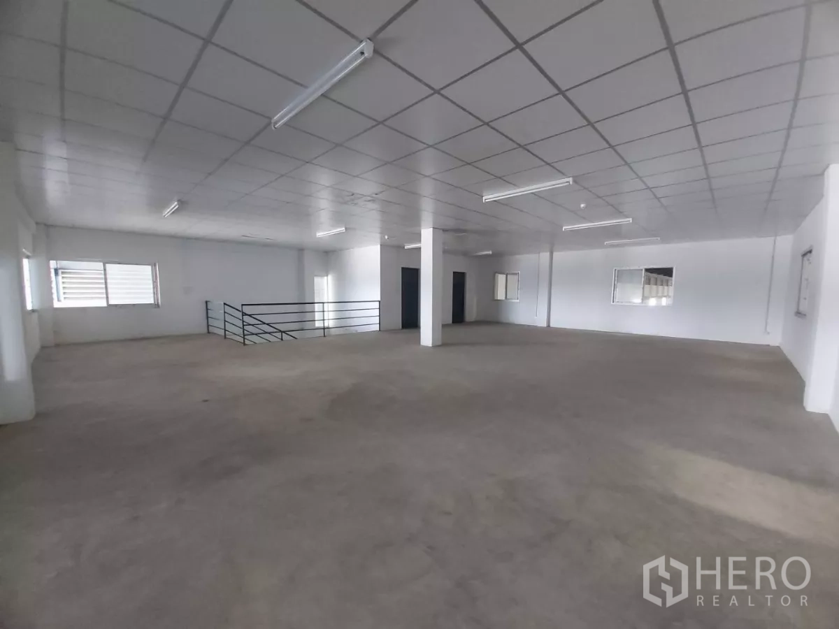 Warehouse for rent in Bang Bo, Samut Prakan - Open-plan office floor with railing, fluorescent lights and ample natural light.