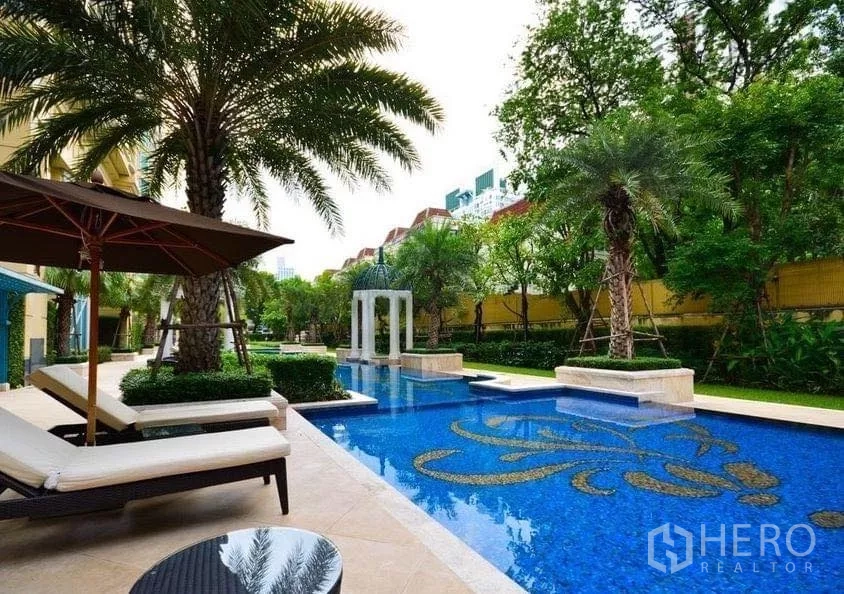 Condominium for sale in Watthana, Bangkok - Resort-style outdoor swimming pool with sun loungers, palm trees and landscaped gardens.