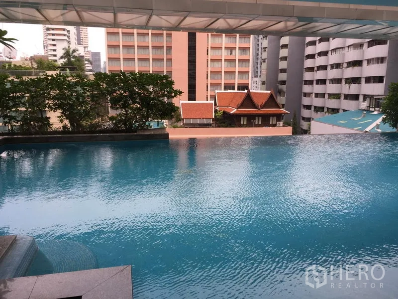 Condominium for rent or sale in Khlong Toei, Bangkok - Infinity-edge swimming pool overlooking nearby buildings and greenery.