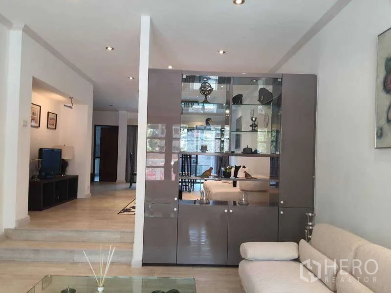 Townhouse for rent in Khlong Toei, Bangkok - Living area with tall display cabinet dividing spaces and spotlight ceiling.