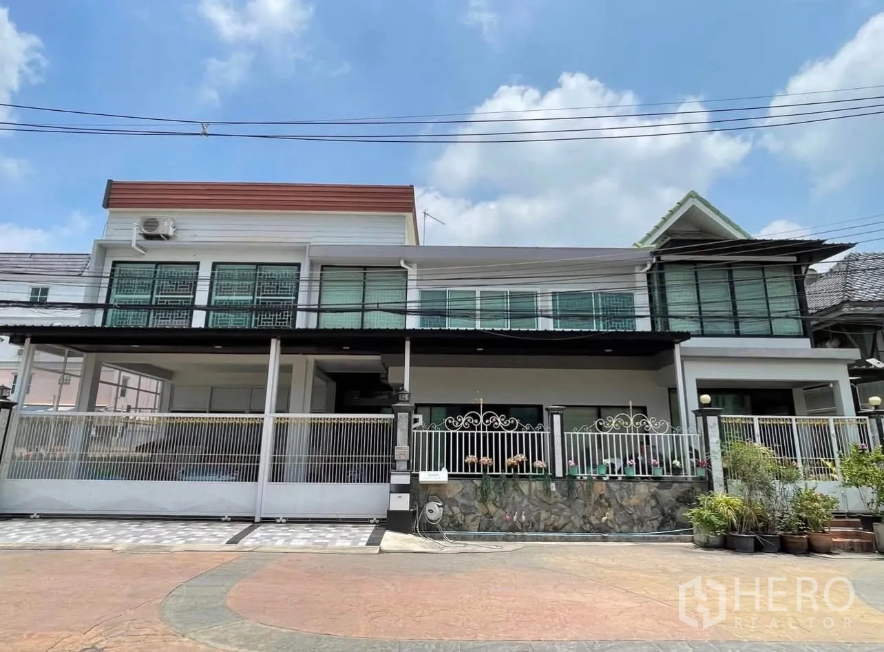 Detached House for rent or sale in Lam Luk Ka, Pathum Thani - Street-facing exterior of a two-storey detached house with gated fence and terrace.