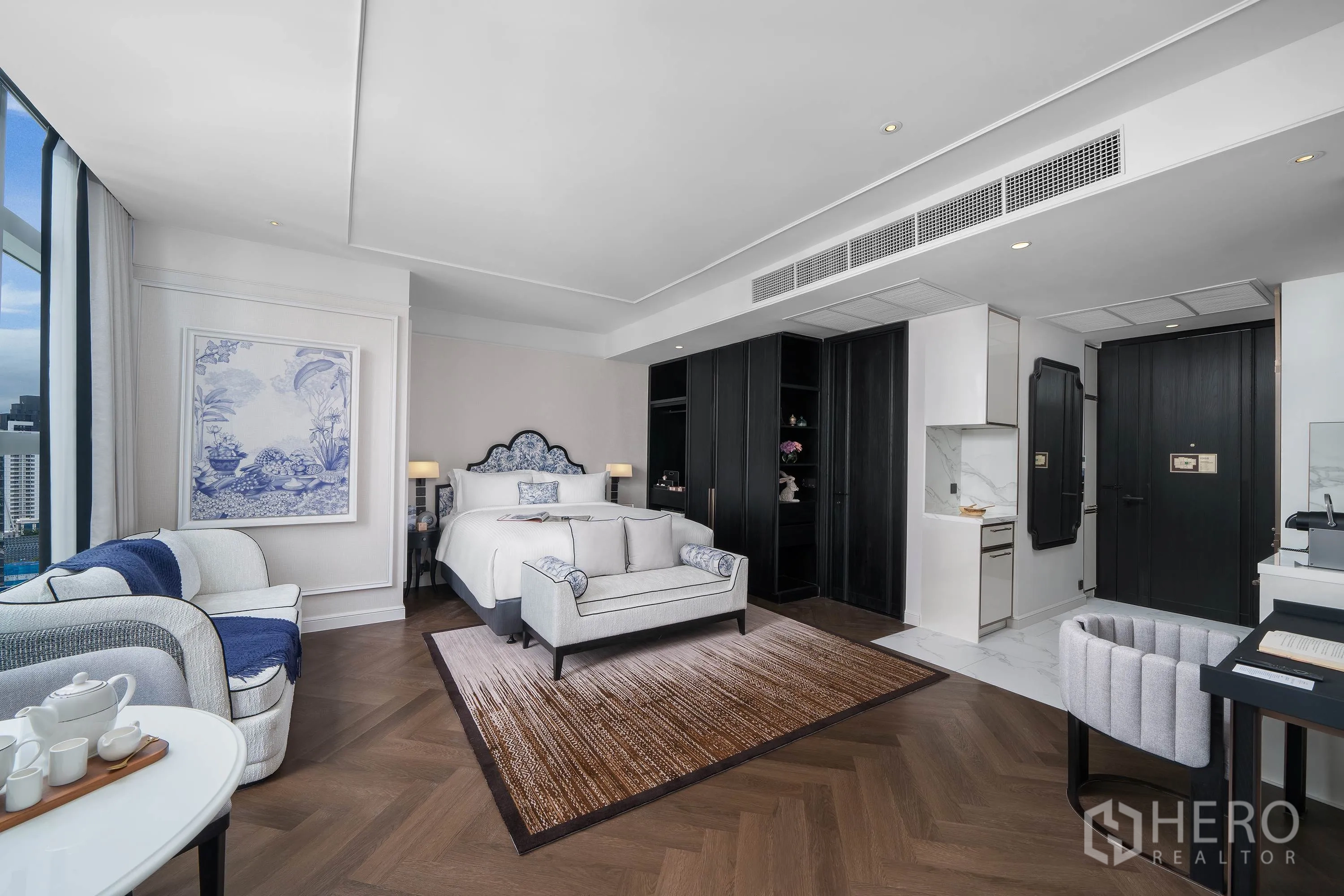 คอนโด for rent in Khlong Toei, Bangkok - ห้องนอนกว้างพร้อมโซฟา พรม ชุดครัว ตู้เสื้อผ้าไม้สีเข้ม และหน้าต่างชมวิวเมือง
