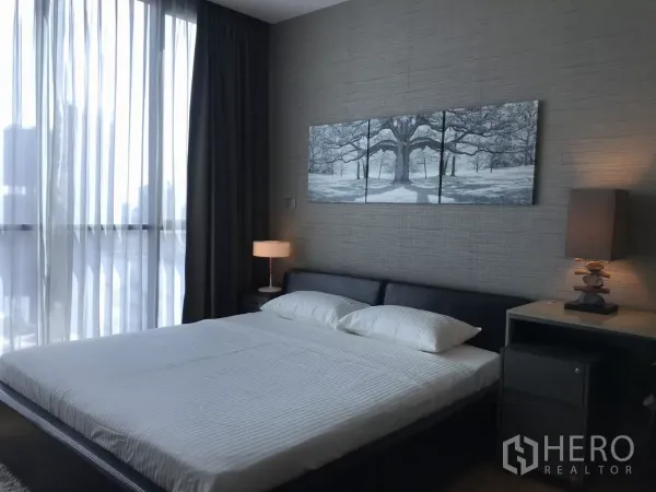 Condominium for rent in Watthana, Bangkok - Primary bedroom with king bed, textured feature wall and floor-to-ceiling curtains.