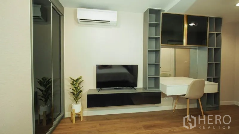 Condominium for rent in Khlong San, Bangkok - Bedroom workspace with built-in shelving, wall-mounted TV, and dressing table.