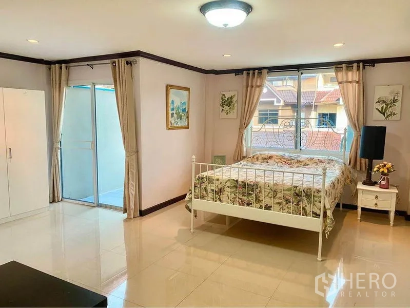 联排别墅 出租或出售在Prawet, Bangkok - 主卧带阳台推拉门，白色金属床与亮面地砖。