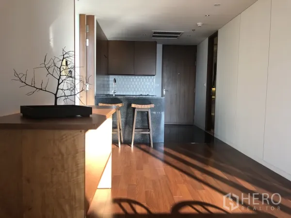 Condominium for rent in Pathum Wan, Bangkok - Compact kitchen with stone island breakfast bar, stools, tiled backsplash, and built-in cabinetry.