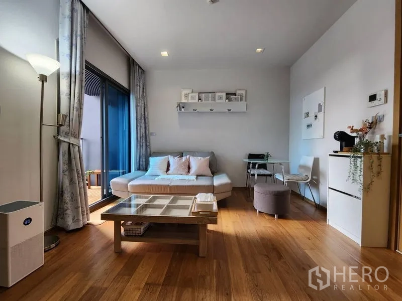 Condominium for rent in Watthana, Bangkok - Airy lounge with floor lamp, wide curtains and access to a private balcony.