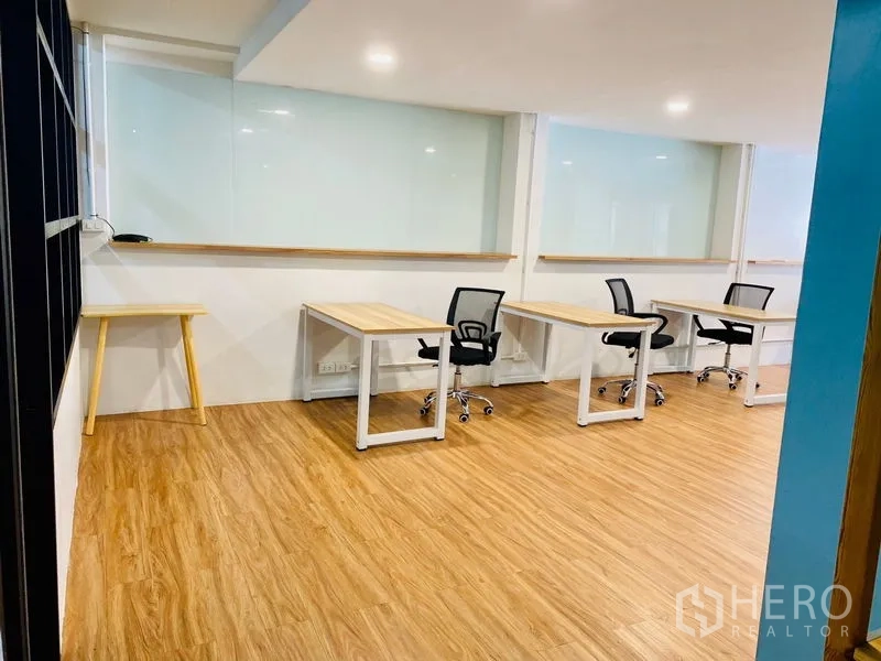 Office Space for rent in Bang Rak, Bangkok - Row of workstations along a wall beside an interior glass partition.
