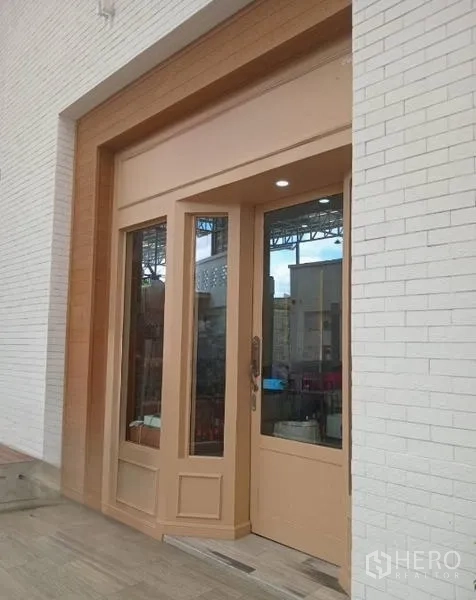 Retail Space for rent in Khlong Toei, Bangkok - Street‑facing shopfront with tall wood‑framed glass door set in a white brick facade.