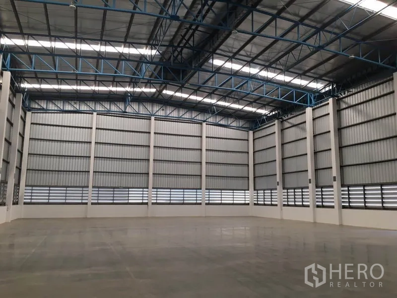 Warehouse for rent in Lat Krabang, Bangkok - Spacious warehouse interior with high steel truss roof, ventilated wall panels, and polished concrete floor.