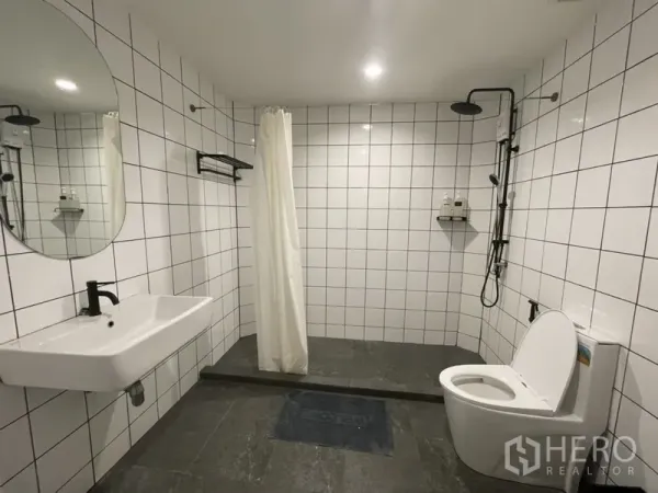 Home Office for rent or sale in Watthana, Bangkok - Spacious tiled bathroom with walk-in rain shower, curtain, wall-hung sink and toilet.