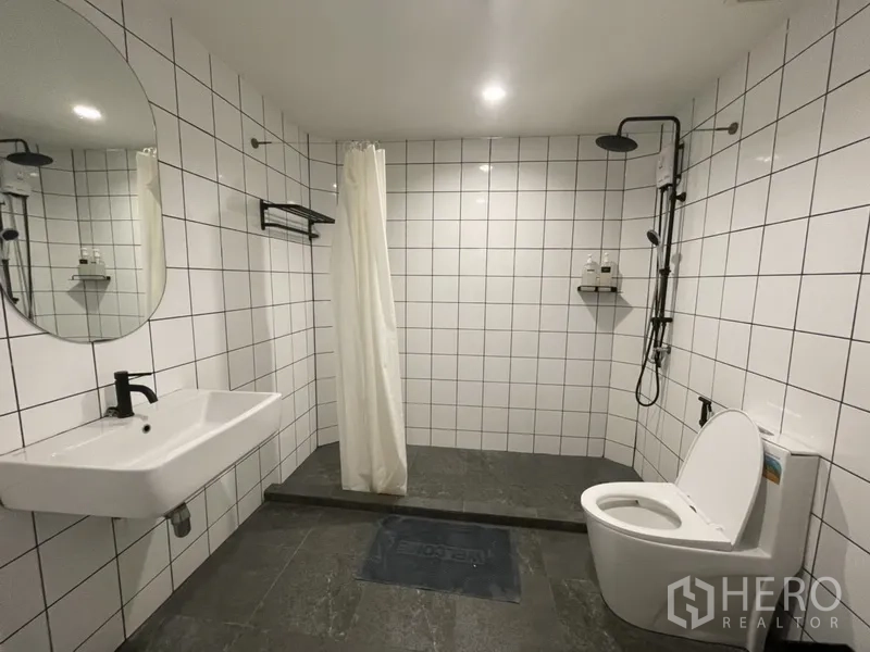 Home Office for rent or sale in Watthana, Bangkok - Spacious tiled bathroom with walk-in rain shower, curtain, wall-hung sink and toilet.