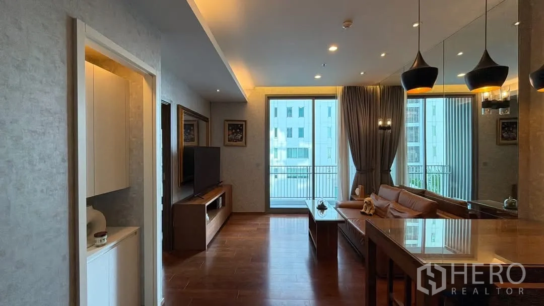 คอนโด for rent in Watthana, Bangkok - พื้นที่นั่งเล่นและรับประทานอาหารโทนอุ่น พื้นไม้ โคมแขวน ผนังกระจกเงา มีชั้นวางทีวี และประตูกระจกเปิดสู่ระเบียง