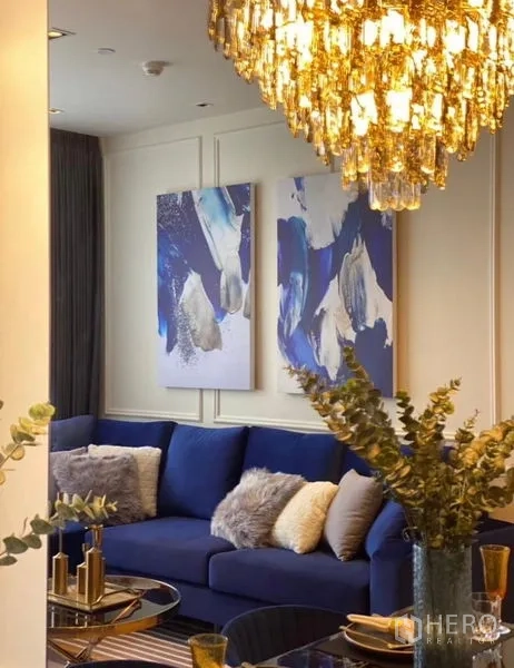 Condominium for rent - View from dining to living area with sectional blue sofa, chandelier and abstract wall art.