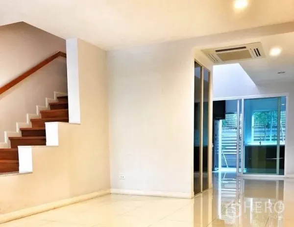 联排别墅 出租在Watthana, Bangkok - 采光充足的客厅，白色地砖与木楼梯