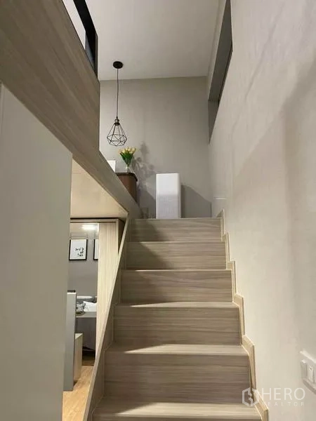 Condominium for rent in Ratchathewi, Bangkok - Wooden staircase leading up to the mezzanine level with pendant light.