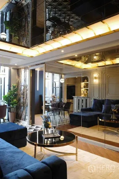 Condominium for sale - Lounge with blue velvet sofa, mirrored wall, and warm ceiling lights.