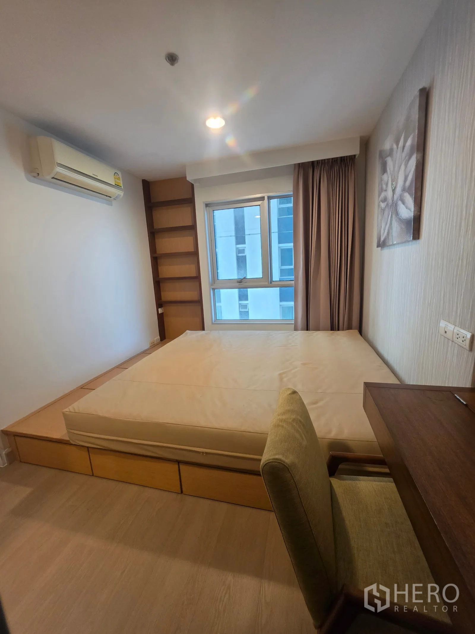 Condominium for rent in Huai Khwang, Bangkok - Bedroom with platform bed, desk and chair, air conditioner, and window.
