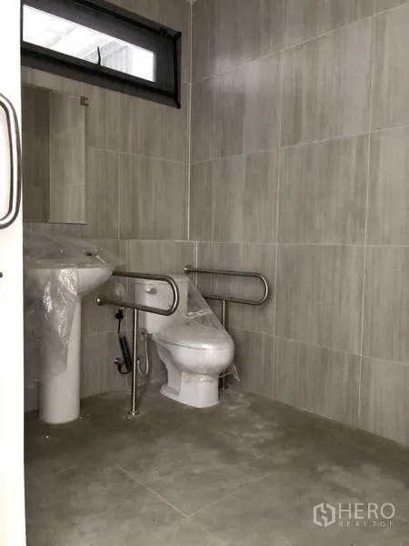 Factory for rent or sale in Samut Prakan - Accessible restroom with grab bars, tiled walls, and sanitary fixtures.