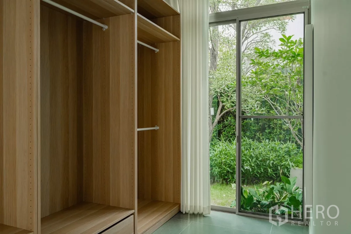 Detached House for rent in Saphan Sung, Bangkok - Walk-in closet with wood cabinetry and door to green garden.