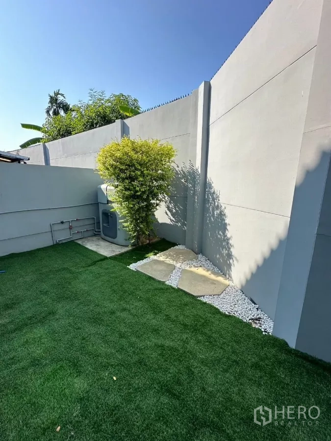 Townhouse for rent in Bang Phli, Samut Prakan - Private backyard with artificial turf, stepping stones and a high wall.