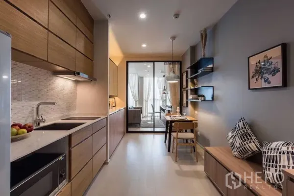Condominium for rent in Pathum Wan, Bangkok - Fitted galley kitchen with wood cabinetry, stone countertop, mosaic backsplash and a cozy dining nook.