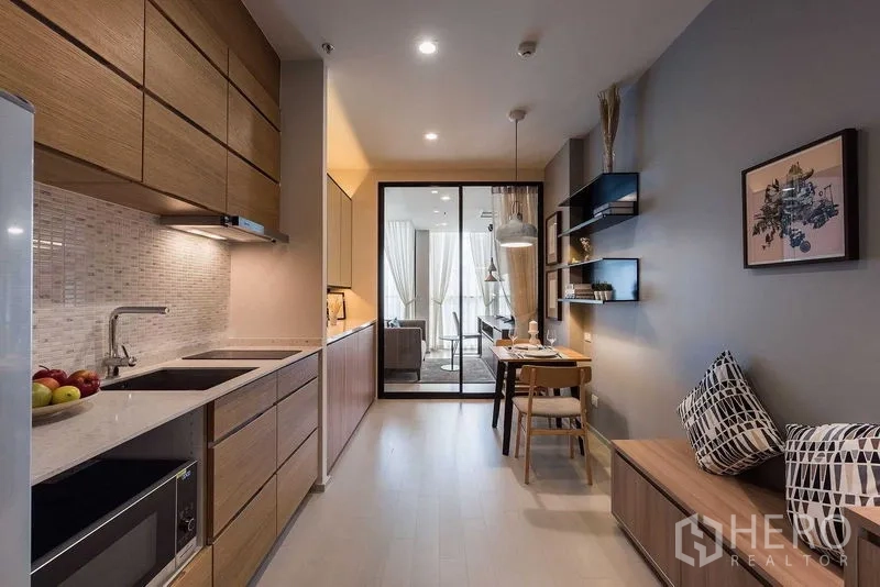 Condominium for rent in Pathum Wan, Bangkok - Fitted galley kitchen with wood cabinetry, stone countertop, mosaic backsplash and a cozy dining nook.
