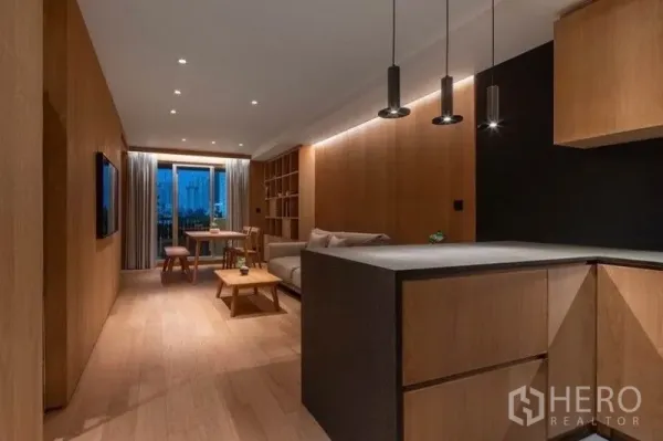 Condominium for rent in Phaya Thai, Bangkok - View from the kitchen into the lounge and dining area with built-in shelves and a balcony beyond.
