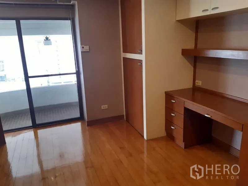 Condominium for rent in Khlong Toei, Bangkok - Work area with built-in desk and shelving, opening to a covered balcony.
