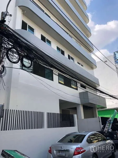 Office Space for rent in Bang Rak, Bangkok - Side elevation of the building with on-street parking and overhead cables.