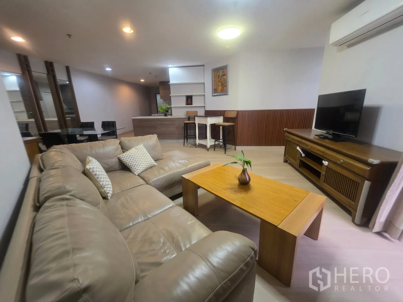 Condominium for rent in Huai Khwang, Bangkok - Open-plan living area with sofa, TV console, dining set, and kitchen bar.