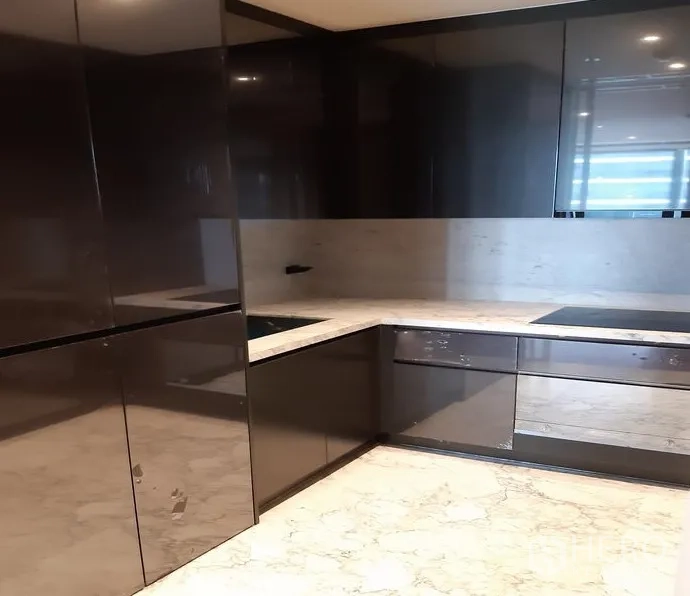 公寓 出租在Watthana, Bangkok - U形现代厨房，亮面柜体、石材台面与电磁炉。