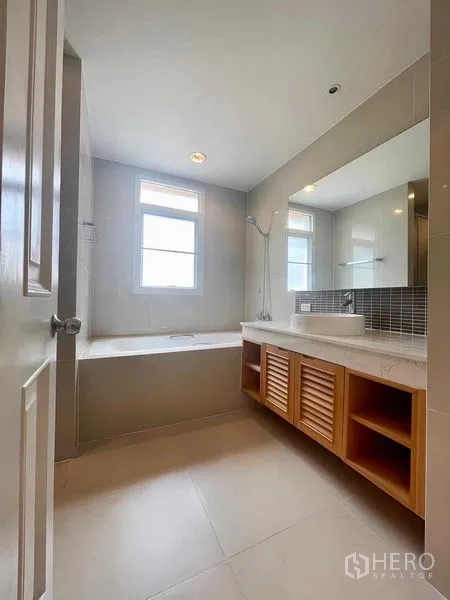 Condominium for rent - Bathroom with a window-side soaking tub, wide mirror and vanity storage.
