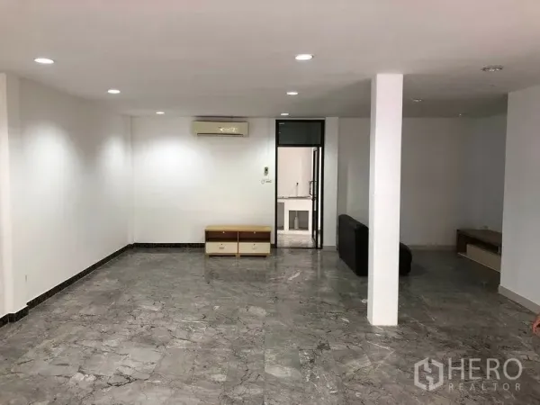 Townhouse for rent in Watthana, Bangkok - Spacious living room with central column, recessed lights, air conditioner and doorway to the kitchen.