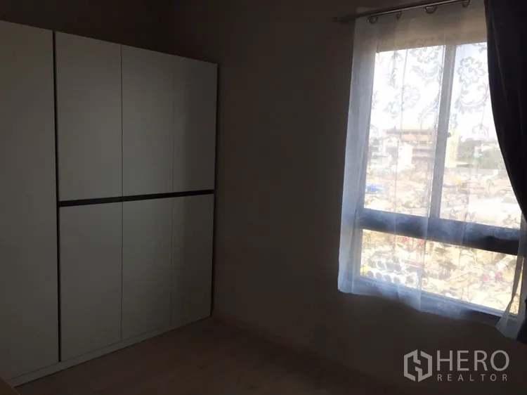 Townhouse for rent in Suan Luang, Bangkok - Compact room with a white wardrobe and a window with sheer curtains.