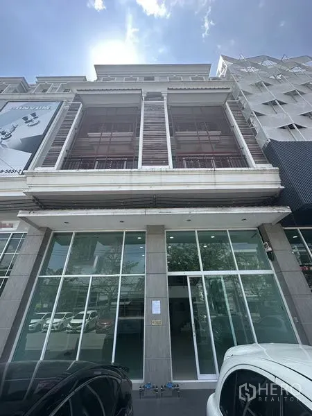 Home Office for rent in Bang Na, Bangkok - Front elevation of multi-storey building with large glass entrance and parking.