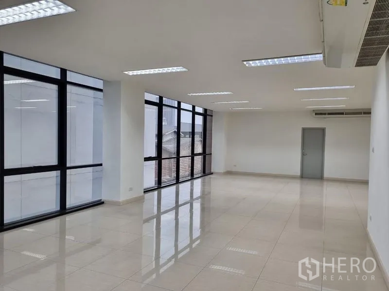 Office Space for rent in Bang Kho Laem, Bangkok - Bright open-plan office with polished tile floors, ceiling lights, and large black-framed windows.