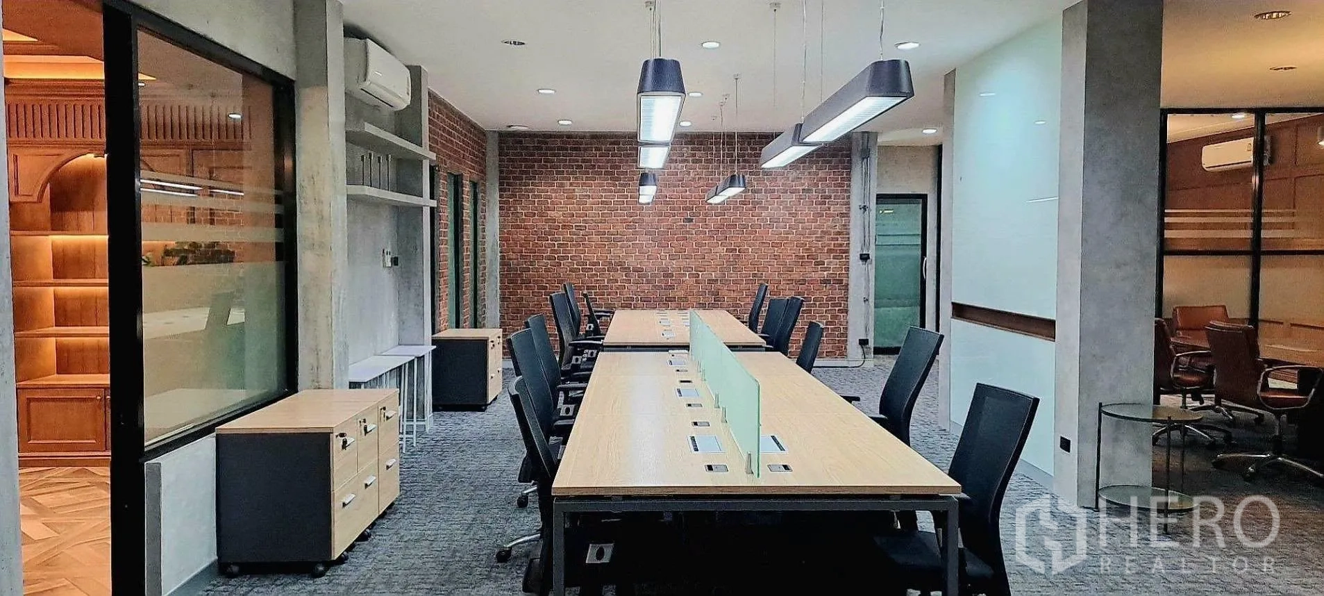 Home Office for rent in Lat Phrao, Bangkok - Open-plan workspace with long bench desks, task lighting and brick accent wall.
