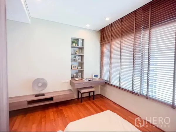 Condominium for rent in Khlong Toei, Bangkok - Bright bedroom corner with built-in desk and shelving, and wide blinds over tall windows.