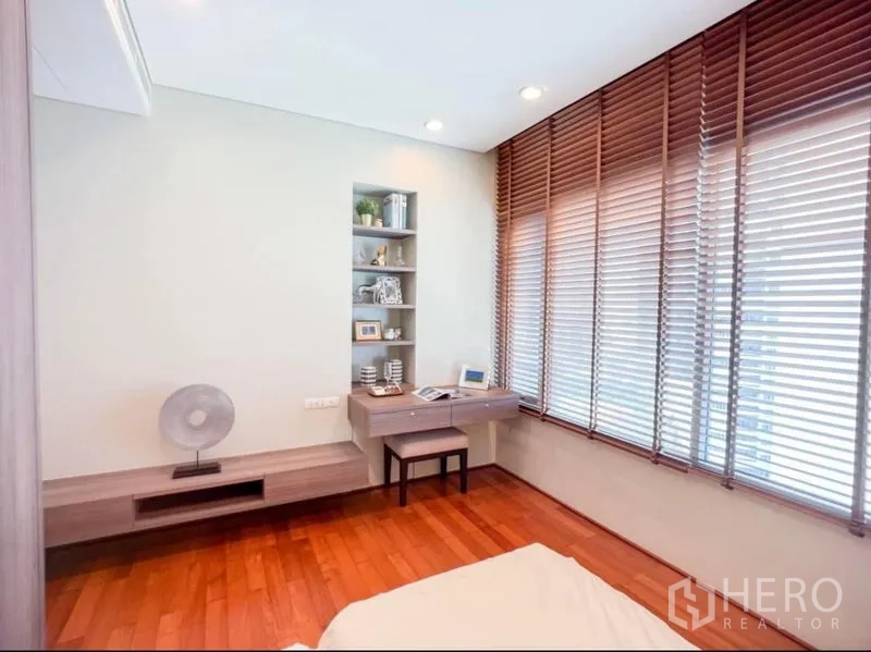 Condominium for rent in Khlong Toei, Bangkok - Bright bedroom corner with built-in desk and shelving, and wide blinds over tall windows.