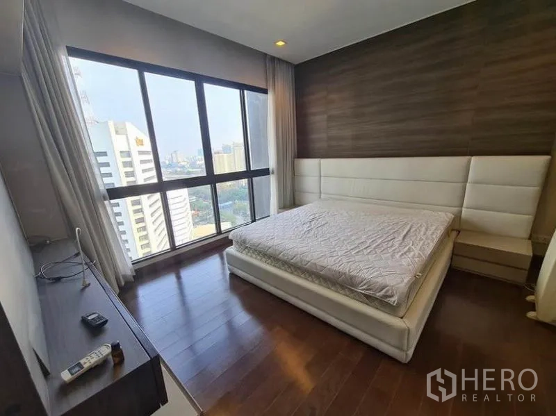 公寓 出租或出售在Huai Khwang, Bangkok - 主卧宽敞，特色墙面与大幅观景窗。
