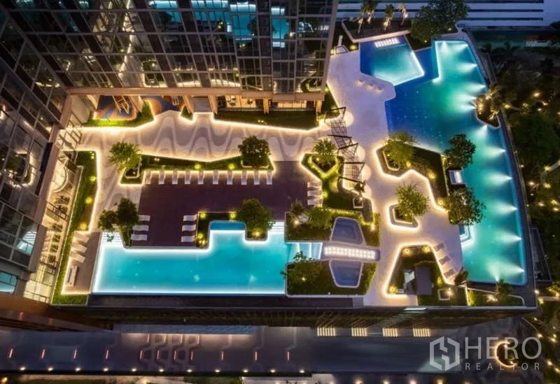 Condominium for rent or sale in Sathon, Bangkok - Aerial night view of resort-style swimming pools, landscaped deck and sun loungers.