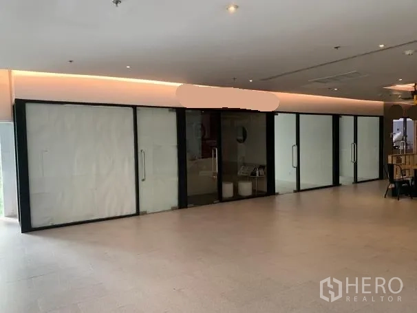 零售空间 出租 - 室内走廊旁的商铺，落地玻璃门面与多扇玻璃门，柔和灯带照明