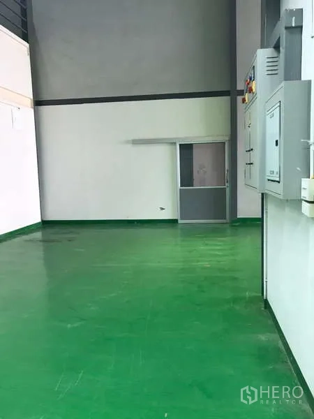 工厂 出租在Bang Phli, Samut Prakan - 干净走道，绿色地坪通向推拉门与配电柜