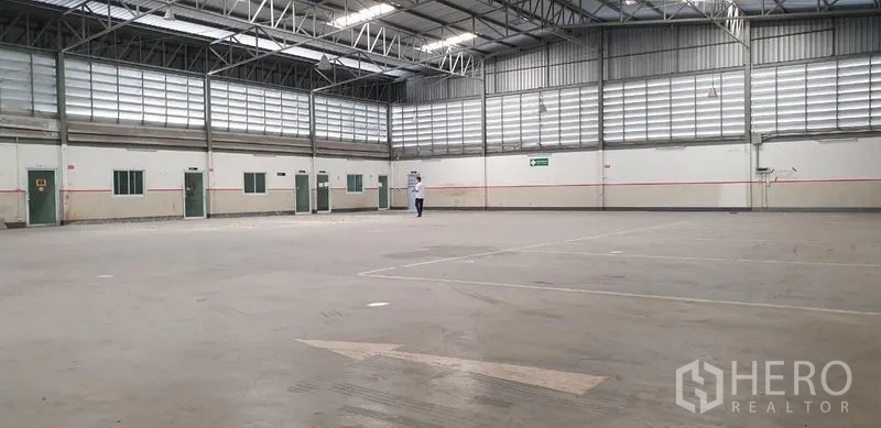 Warehouse for rent in Lam Luk Ka, Pathum Thani - Expansive open warehouse floor with high ceilings, skylights, and ventilation louvers.
