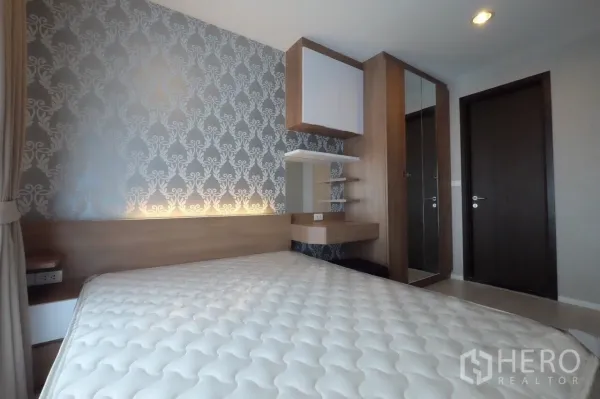Condominium for rent in Sathon, Bangkok - Close-up of the bedroom feature wall with built-in shelves, dressing nook and mirrored wardrobe.