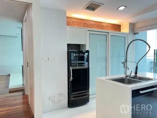 公寓 出租在Khlong Toei, Bangkok - 现代厨房一角，岛台水槽、恒温酒柜与磨砂玻璃门。