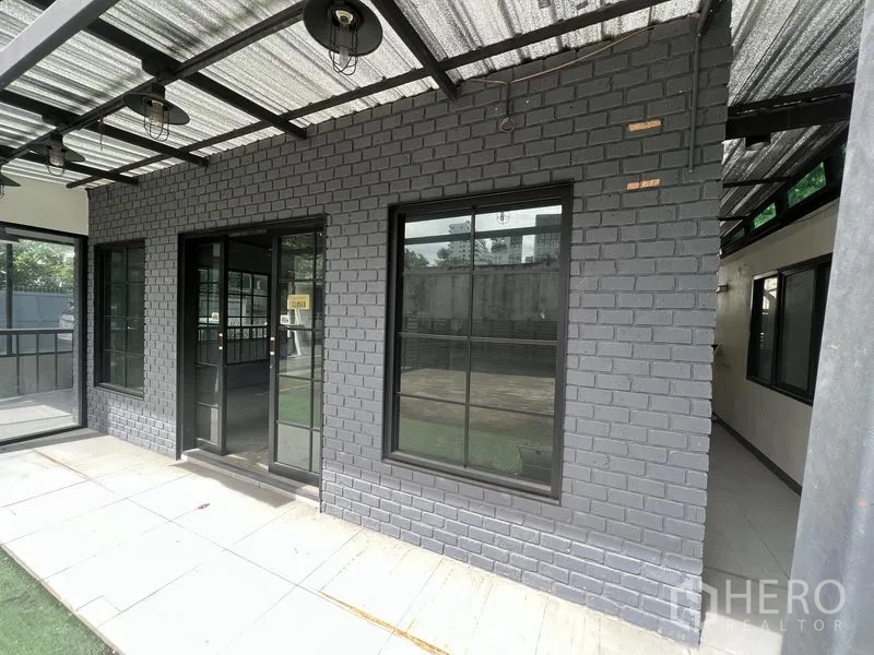 Retail Space for rent in Watthana, Bangkok - Gray brick storefront with black-framed windows and double glass doors under a canopy.