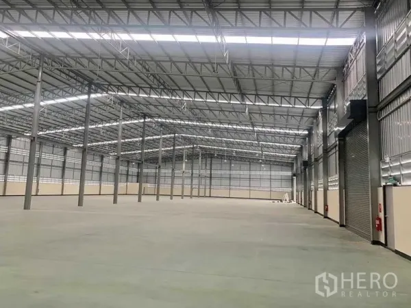 货栈 出租在Ban Bueng, Chon Buri - 宽敞仓库内部，高钢结构屋顶、平整混凝土地面与卷闸门，设消防设施。