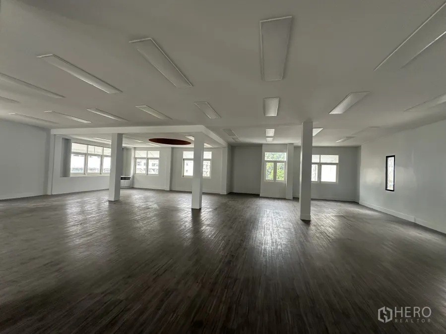 Retail Space for rent in Bang Rak, Bangkok - Spacious open-plan retail floor with wood-look flooring, columns and large windows.